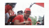 a man in a red shirt and red hat is surrounded by other men .
