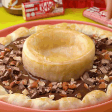 a pizza covered in chocolate and nuts with a box of kitkat behind it