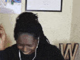 a woman with dreadlocks is wearing headphones and smiling in front of a wooden w