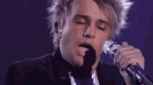 a young man is singing into a microphone .