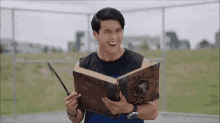 a man is holding a book with a dragon on it and smiling