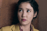 a woman wearing a yellow jacket and a pink shirt looks at the camera