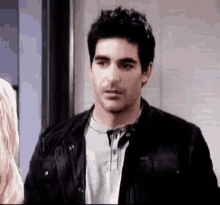 a man in a black jacket is standing next to a woman in a doorway .