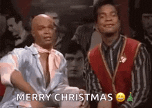 two men are sitting next to each other in a room and one of them is wearing a red sweater .