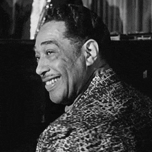 a man wearing a leopard print shirt is smiling in a black and white photo