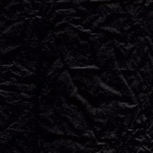 a crumpled piece of black paper with a cross in the corner
