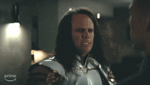 a man with long hair is talking to another man with a prime logo behind him