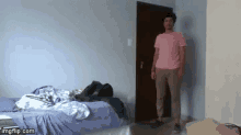 a man in a pink shirt is standing in front of a bedroom door