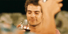 a man in a pink shirt is holding a glass of wine in his hand