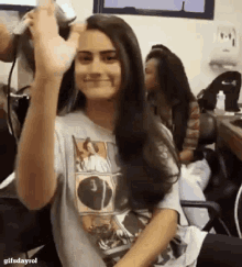 a woman in a t-shirt is getting her hair done