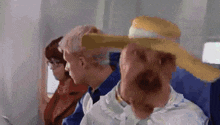 a man wearing a straw hat is sitting on an airplane with other people .