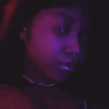 a close up of a woman 's face with purple and pink lights behind her .