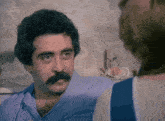 a man with a mustache is talking to another man