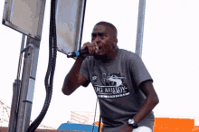a man singing into a microphone wearing a shirt that says ' big muddy '