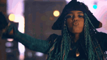 a woman with blue dreadlocks is wearing a pirate hat and blowing a kiss