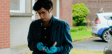 a man wearing blue gloves is standing in front of a white car