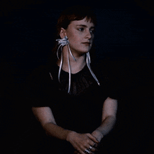 a woman wearing a black top with white ribbons around her neck