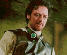 a man with a beard is wearing a leather vest with a green button on the collar .