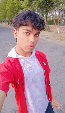 a young man wearing a red shirt and a white t-shirt takes a selfie