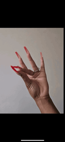 a woman 's hand with red nails and a silver ring