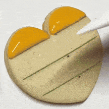 a heart shaped cookie is being decorated with yellow and green stripes