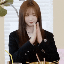 a girl in a school uniform is clapping her hands in front of a pot of food