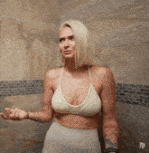 a woman in a white bra stands in front of a tile wall