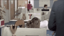 a woman sitting at a desk in an office with a trophy on it
