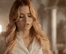 a woman with long blonde hair is wearing a white shirt and a necklace .