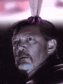a close up of a man with a purple object on his head