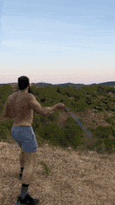 a man without a shirt is standing in a field holding a hose