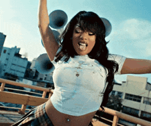 a woman wearing a white crop top and plaid skirt is dancing on a bridge