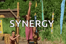 a group of people are standing in a field with the word synergy written on the bottom .