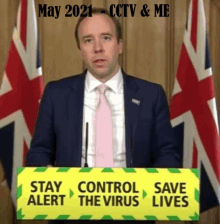 a man in a suit and tie is standing behind a podium with a sign that says stay alert control the virus save lives .