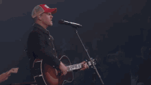 a man singing into a microphone while playing a guitar on stage
