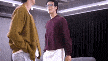 two men are standing next to each other and talking in a room .