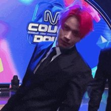 a man in a suit with red hair is standing in front of a m count logo