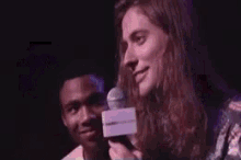 two men with long hair are smiling and laughing on a stage