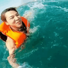 a man wearing a life vest is swimming in the ocean