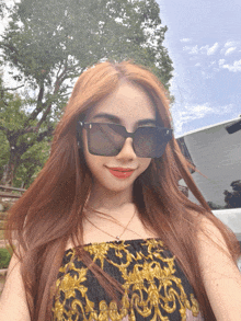 a woman wearing sunglasses and a gold top poses for a photo