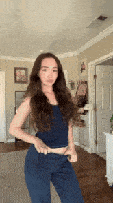 a girl in a blue tank top and blue pants is standing in a room