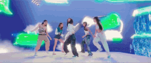 a group of young women are dancing on a stage in front of a green background .