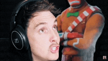 a man wearing headphones is making a funny face in front of a gingerbread man .