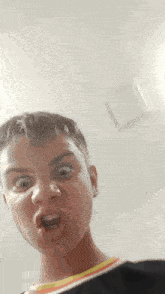 a young man is making a funny face in front of a white wall .