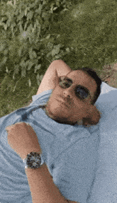 a man wearing sunglasses is laying in the grass