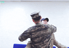 a man in a military uniform holds another man in his arms