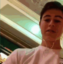 a young man wearing headphones and a white shirt is taking a selfie .