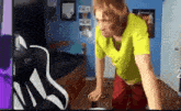 a man in a yellow shirt and red pants is doing push ups on a bed .
