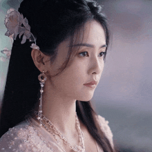 a close up of a woman 's face wearing a necklace and earrings