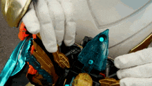 a person in a white glove is holding a blue object with a blue light on it